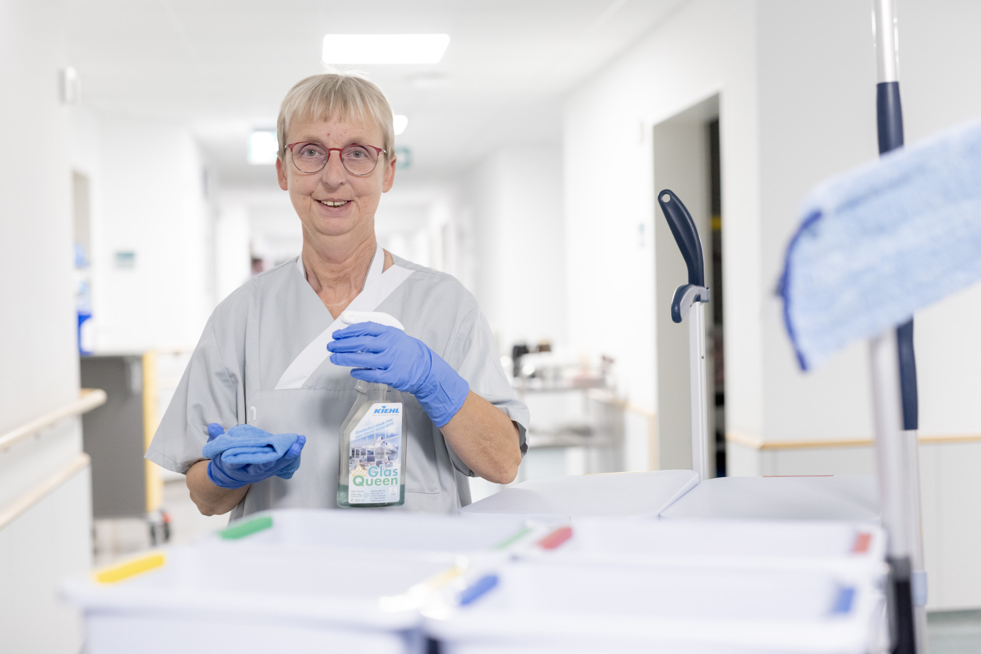 Eine Person im Krankenhaus mit Handschuhen hält ein Desinfektionsmittel und ein Papiertuch.