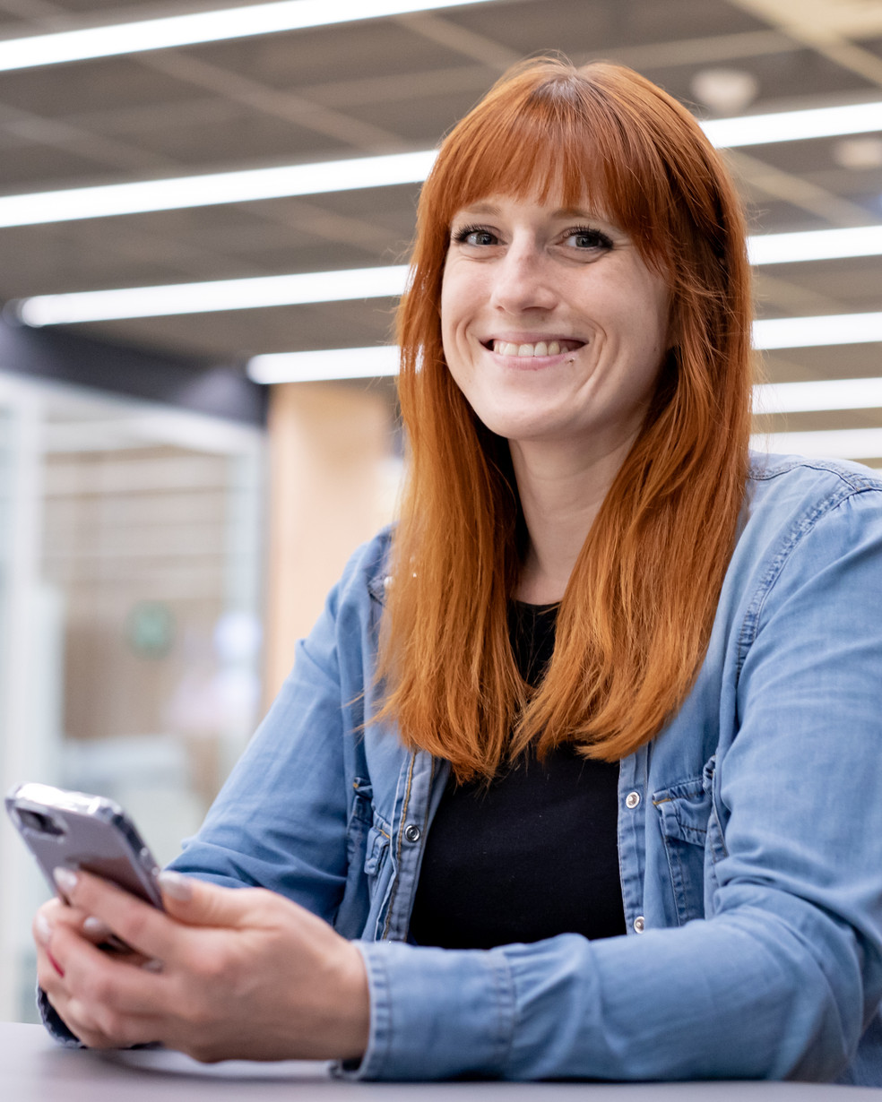 Eine Frau mit roten Haaren und Handy