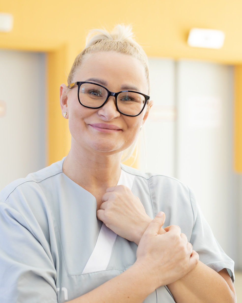 Eine blonde Frau steht vor einer gelben Wand