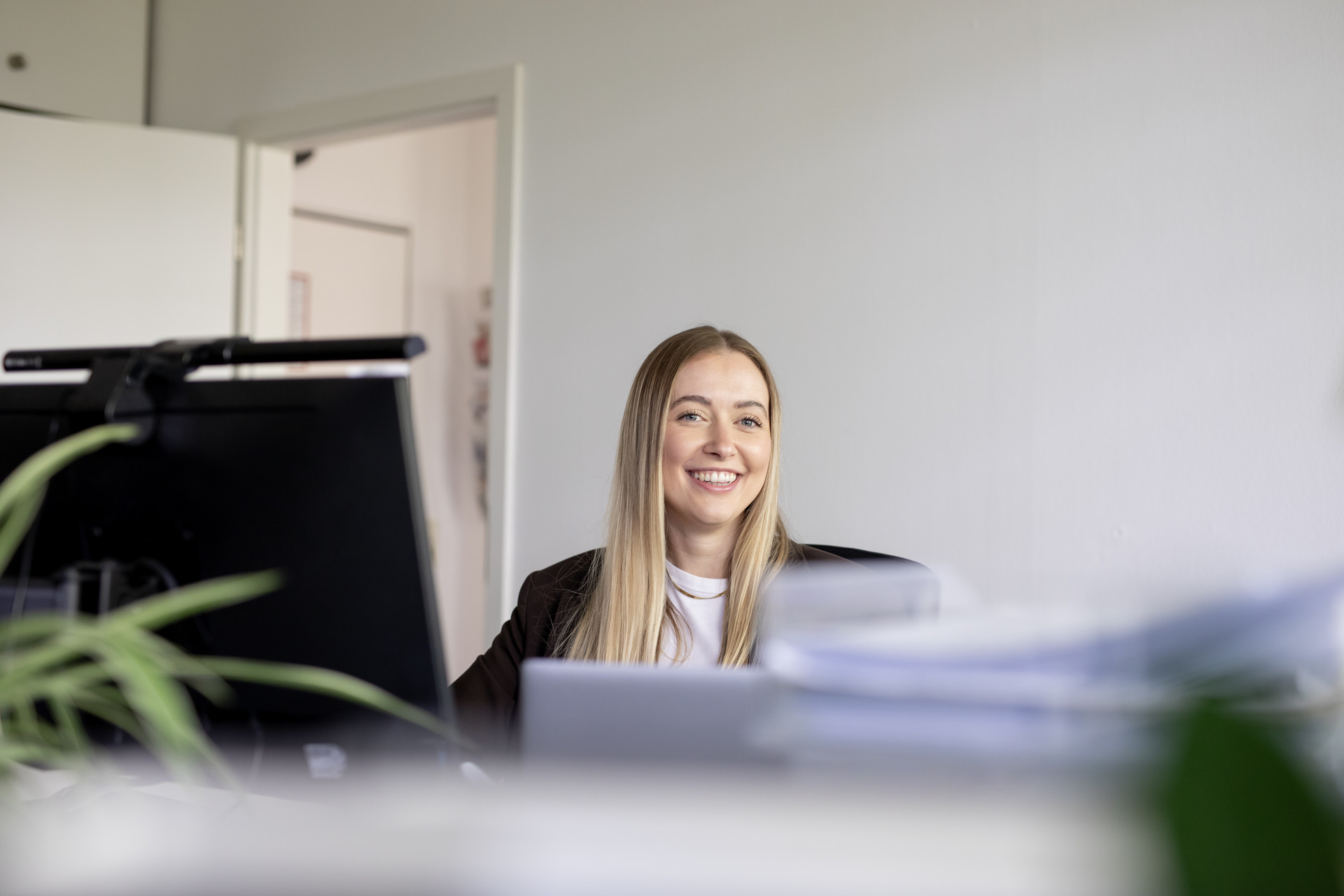 Junge Frau mit blonden glatten Haaren sitzt an einem Schreibtisch