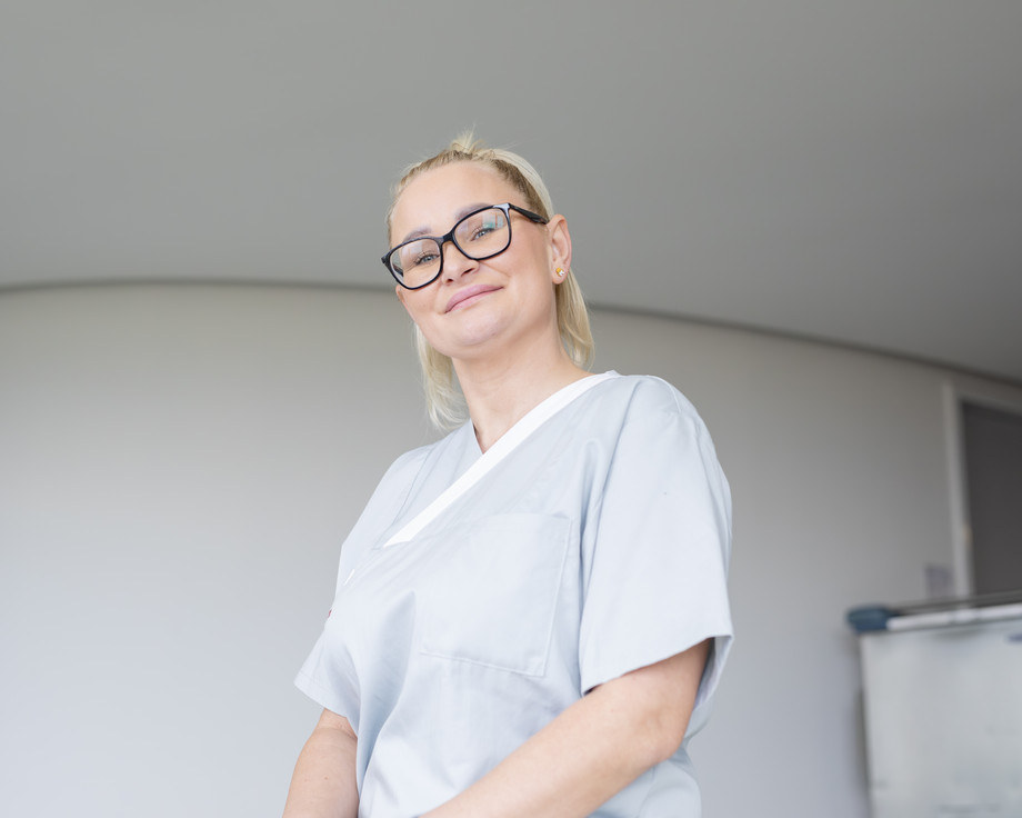 Eine blonde Frau lächelt in hellgrauer Uniform in die Kamera