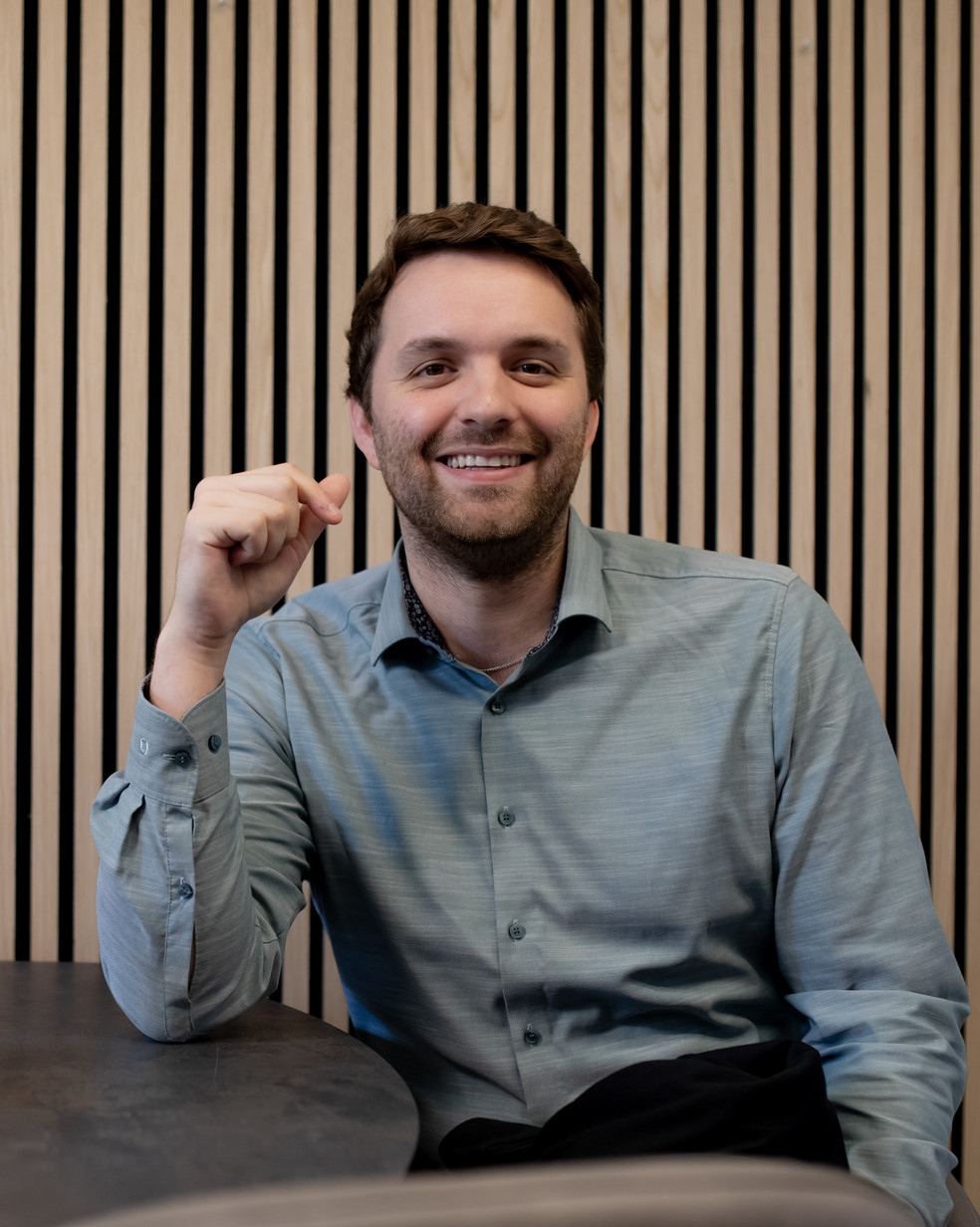 Ein Mann sitzt vor einer Holzwand