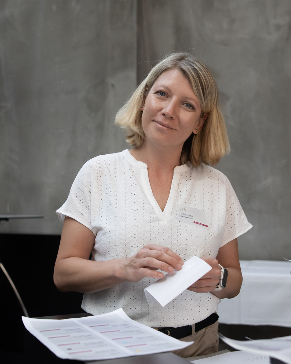 Junge Frau in weißer Bluse steht vor einer grauen Wand