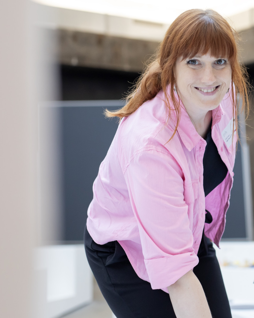 Eine Frau mit roten Haaren und pinkfarbenem Hemd und ein Mann im blauen Hemd