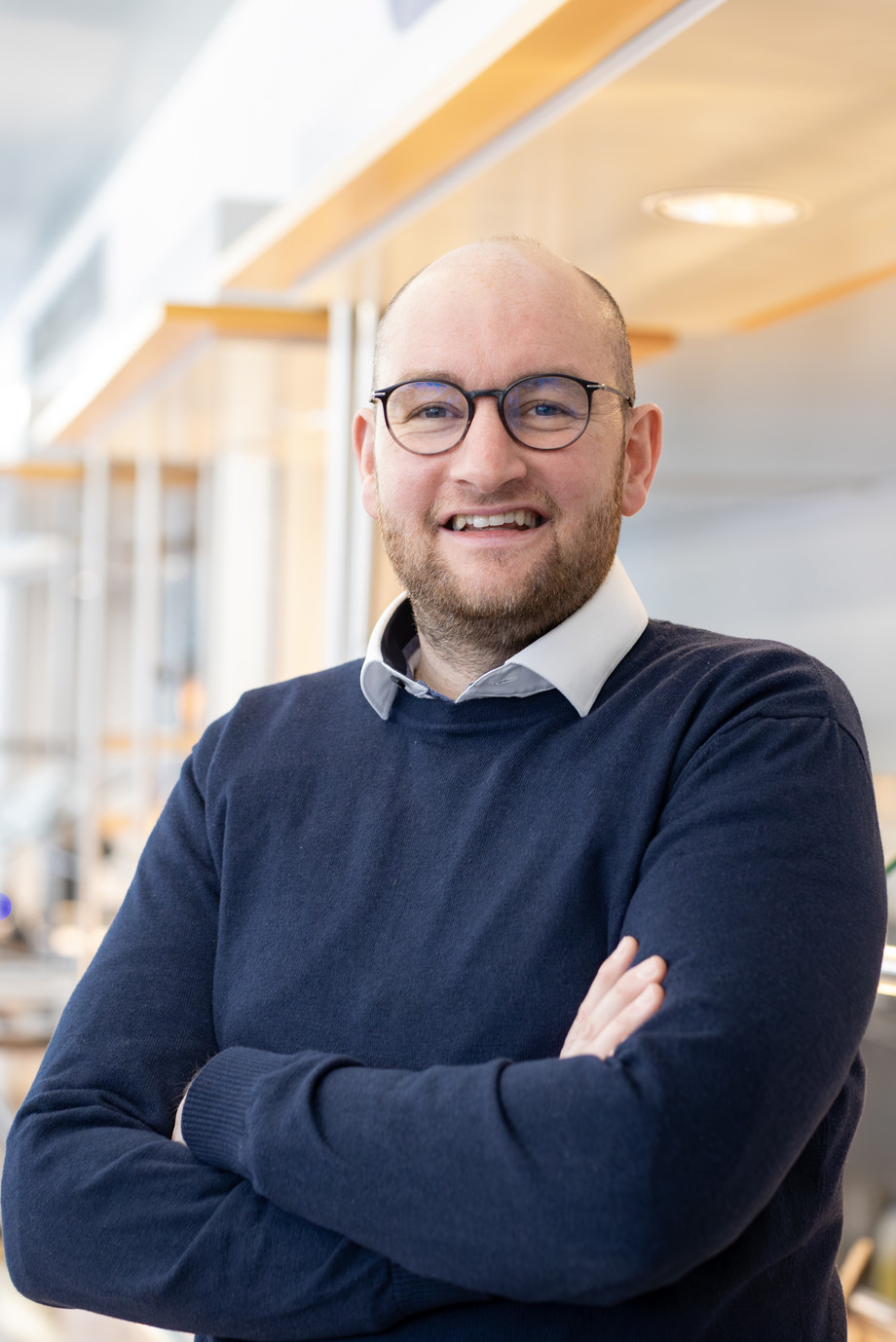 Mann in blauem Pullover steht vor einer Essensausgabetheke