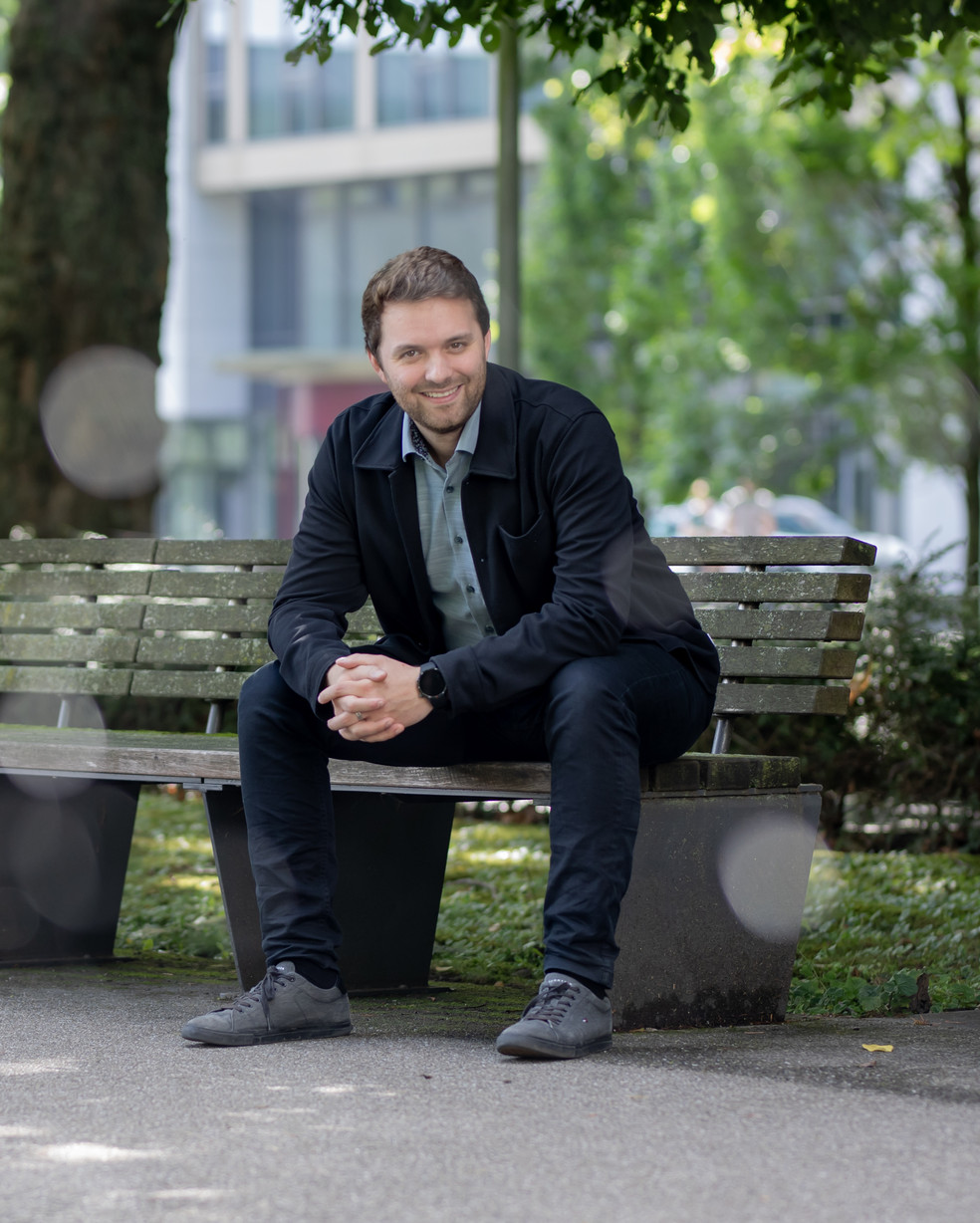 ein Mann sitzt auf einer Bank unter Bäumen