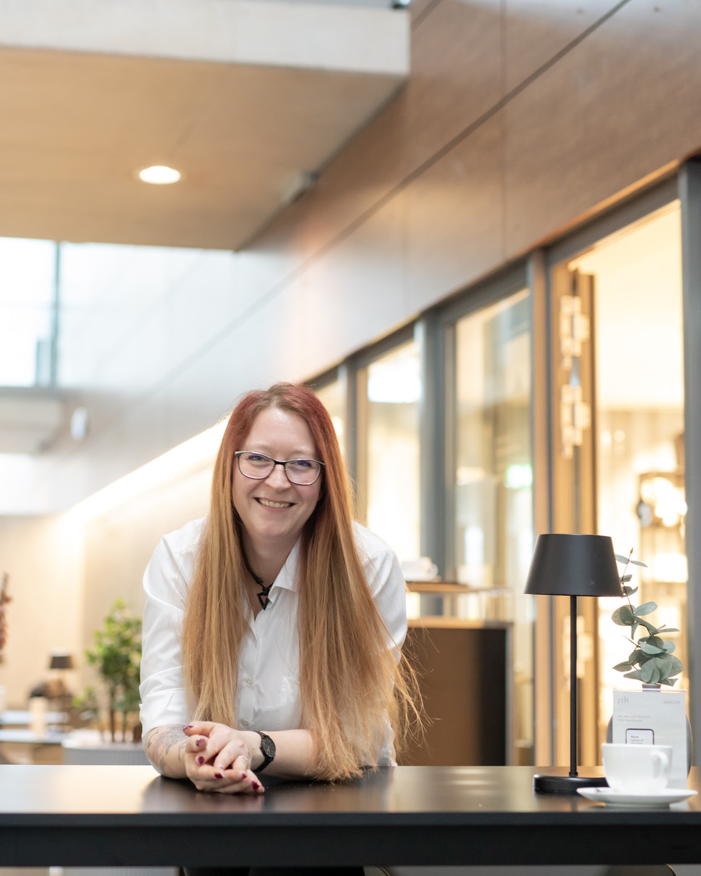 eine Frau in weißer Bluse sitzt vor einem Café und lächelt