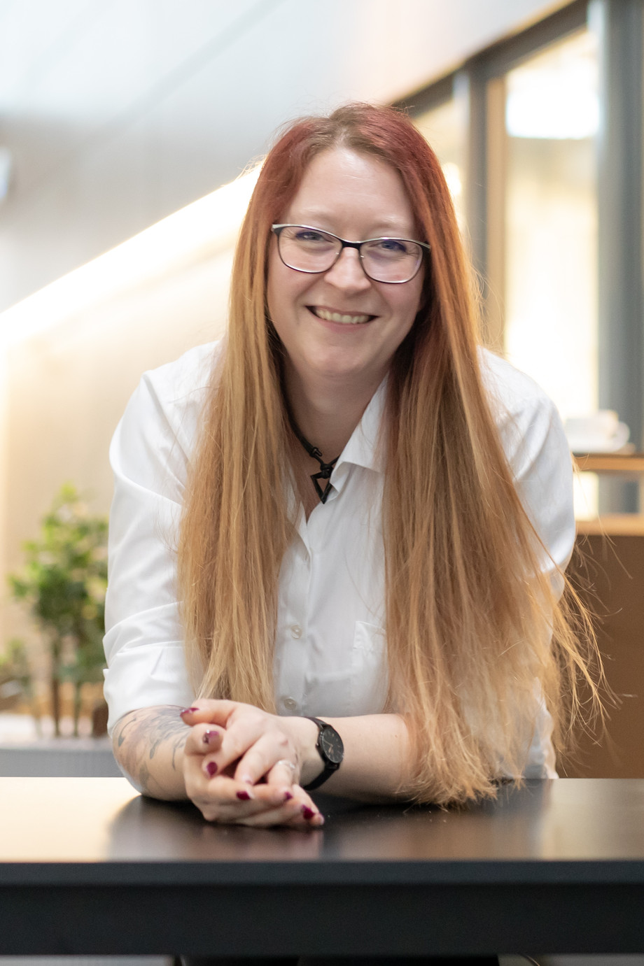 eine Frau in weißer Bluse sitzt vor einem Café und lächelt