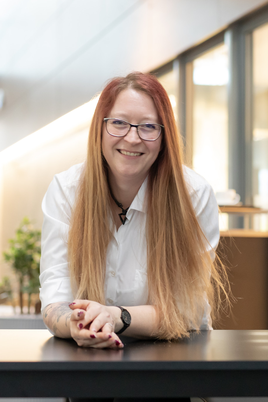 eine Frau in weißer Bluse sitzt vor einem Café und lächelt