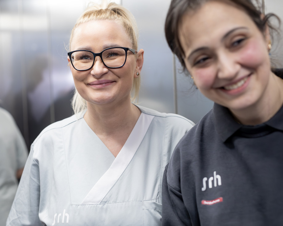 Zwei Frauen im Fahrstuhl lächeln in die Kamera